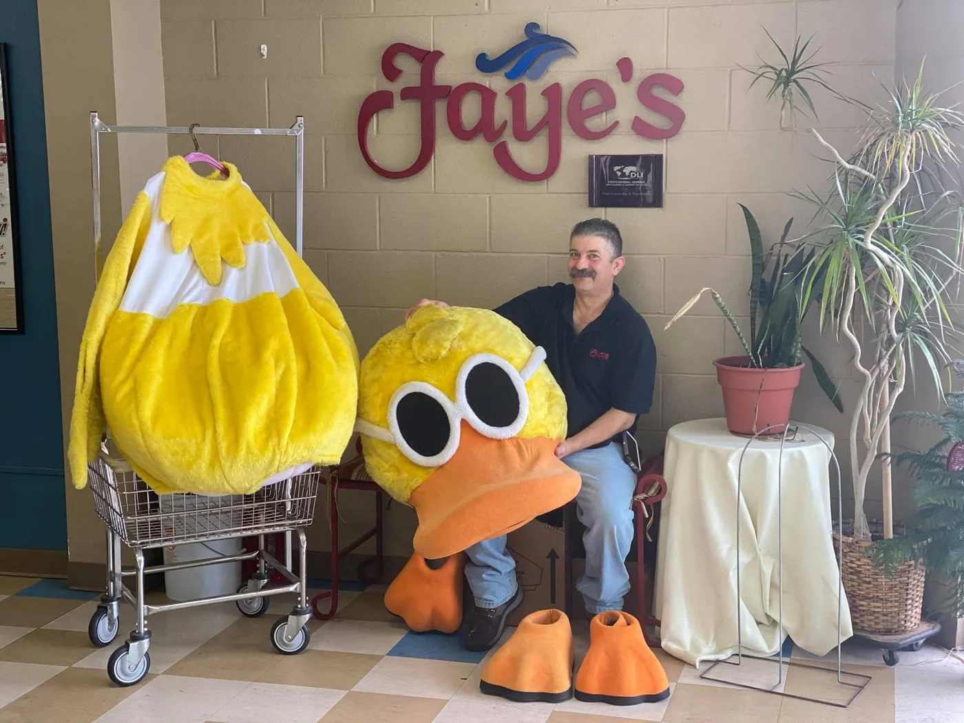 A duck costume displayed with Faye's staff beside the Faye's wall sign