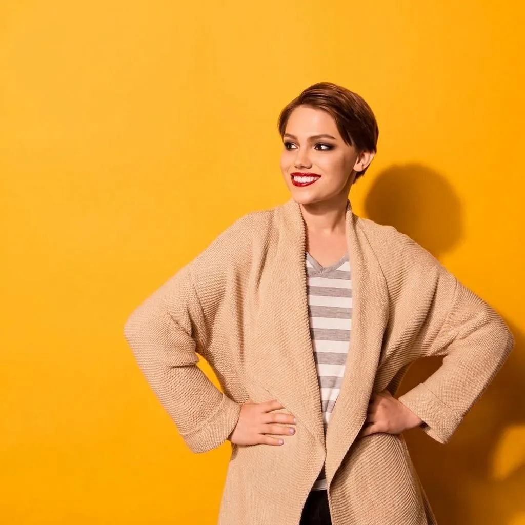 A tan knit cardigan against a mustard backdrop