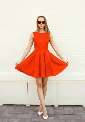 A woman wearing a bright red sleeveless dress and white heels
