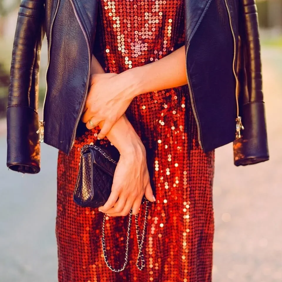 A red sequined dress styled with a leather jacket and purse
