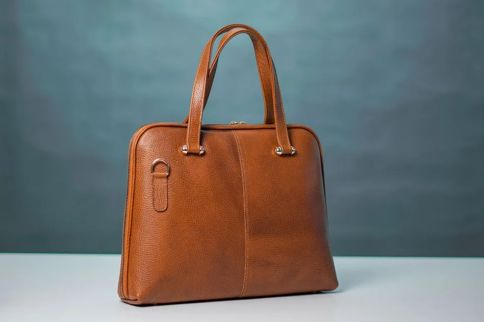Brown leather purse with two handles and gold-tone hardware