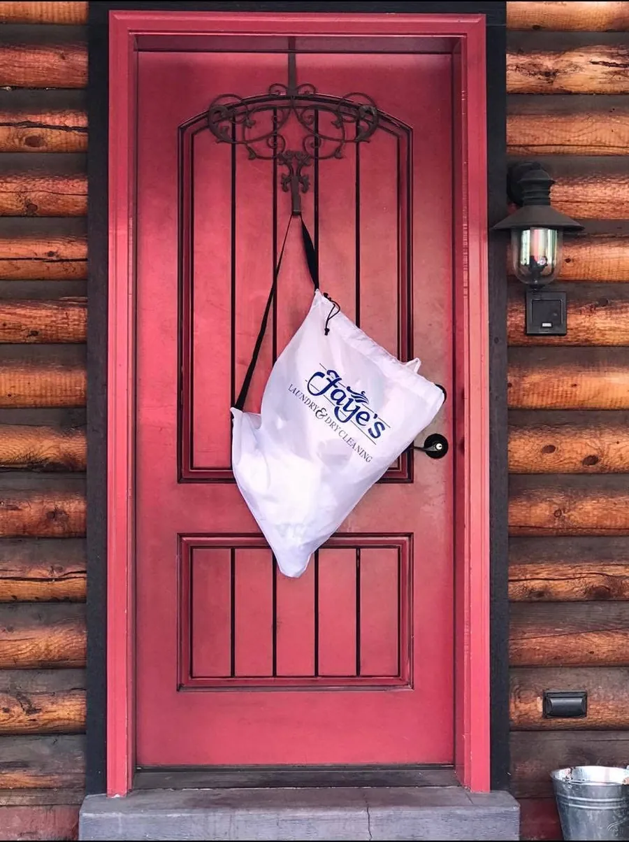 A white Faye's valet bag hanging from a red door