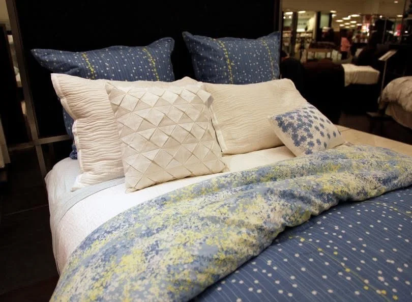 Cream and blue decorative pillows arranged on a patterned bed