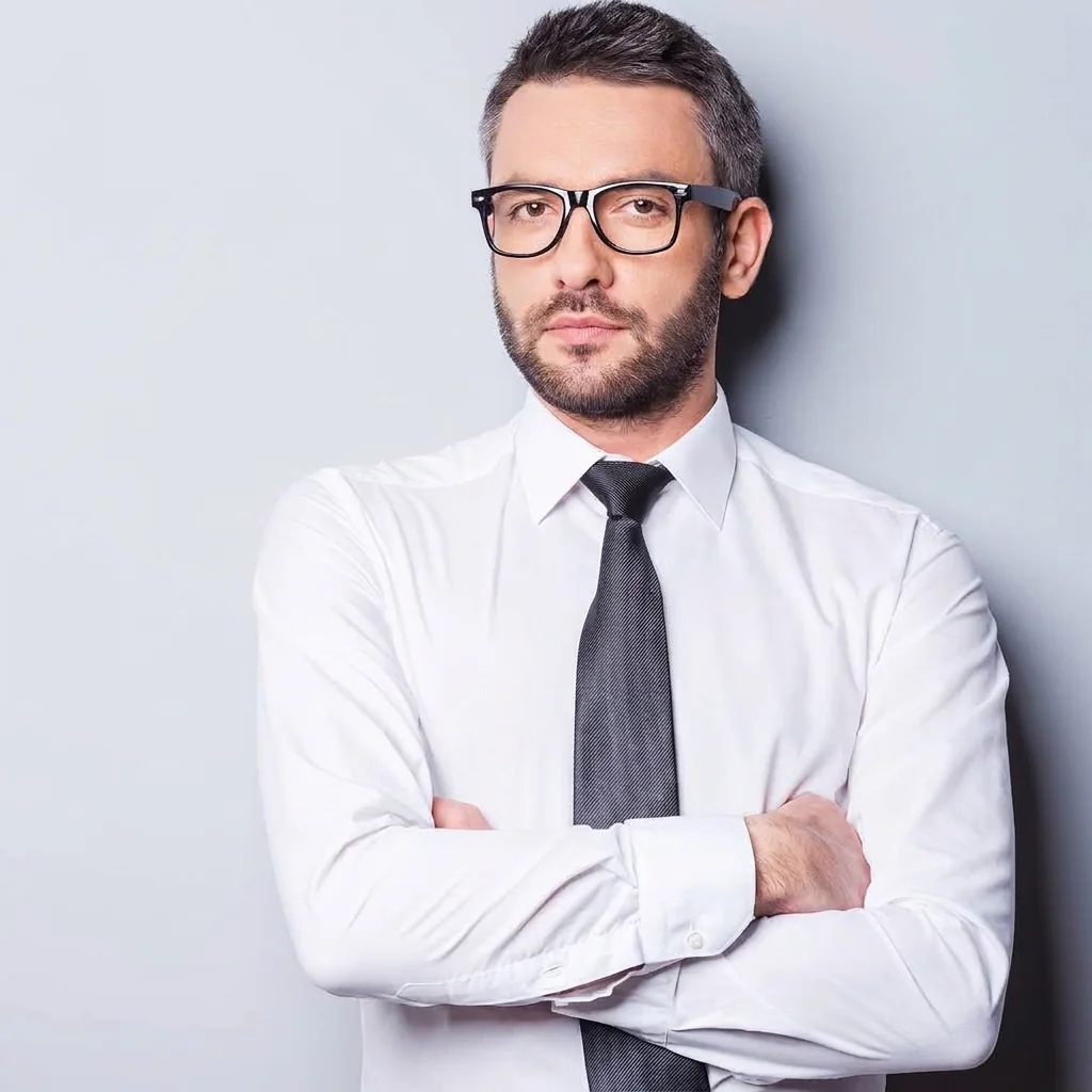 A man in a white dress shirt and glasses with his arms crossed